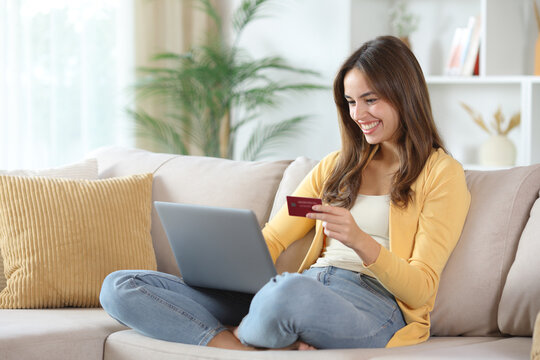 Happy woman in yellow paying online at home