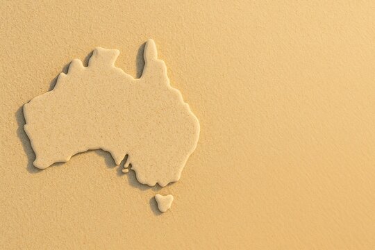 Australia map shape sculpted in beach sand, symbol of travel, tourism, summer holiday and Australian identity in coastal setting, copy space.