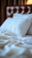 A bed with two white pillows and a blanket. The pillows are neatly arranged and the blanket is spread out. The bed looks clean and inviting, creating a sense of comfort and relaxation