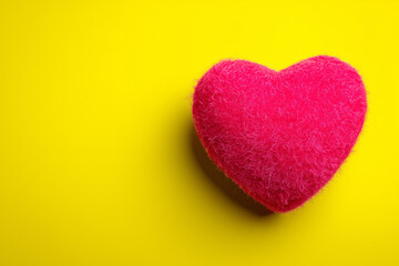 Obraz premium Vibrant pink heart on bright yellow background for love and care concepts