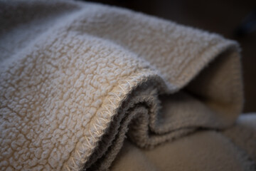 Macro shot of a soft, warm, cream-colored sherpa fleece fabric. The focus is on the textured material and stitched edge, creating a cozy and comfortable background. ©  Colorshadow