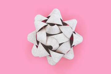 Silver glitter ribbon gift bow for present, greeting card, gift tag, label. Decorative contrast minimal abstract design on pink background.
