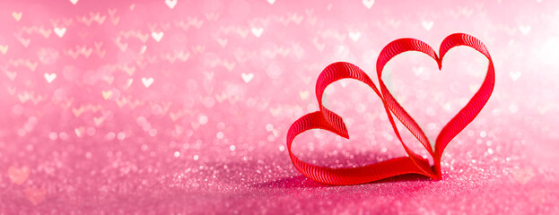 Red ribbon shaped hearts on a bright pink background - Valentine's Day, Wedding and Love Decoration