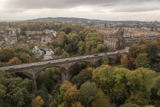 Aerial view of the Dean Bridge gracefully arches over the Water of Leith, a stone testament amidst the vibrant autumn foliage, Moray Feu, Scotland, United Kingdom.