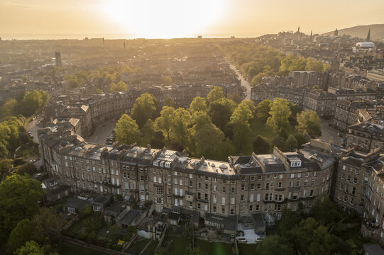 Aerial view of golden sunlight casting long shadows across the elegant crescents and verdant gardens of Moray Feu, creating a tapestry of light and shadow, Moray Feu, Scotland, United Kingdom.