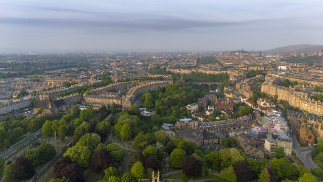 Aerial view of the elegant crescents of Moray Feu embraced by lush greenery, bathed in soft light, contrasting with the urban landscape, Moray Feu, Scotland, United Kingdom.