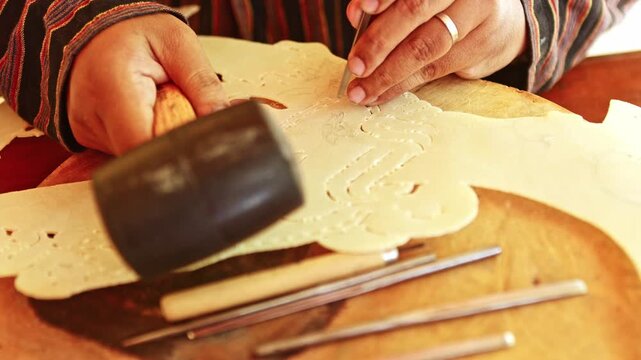 Indonesian artisan carving a traditional wayang kulit shadow puppet