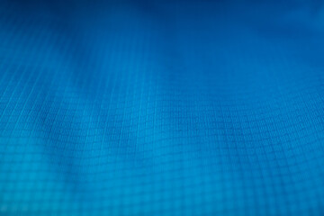 Macro detail of a vibrant blue technical fabric with a ripstop grid pattern. Ideal background for...