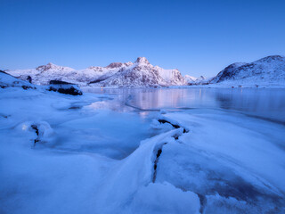 Lofoten islands, Norway. Nature in the fjords during winter night. Mountains, ice and reflections. Scandinavia. Vacation and travel in the winter north. Background, wallpaper, postcards.