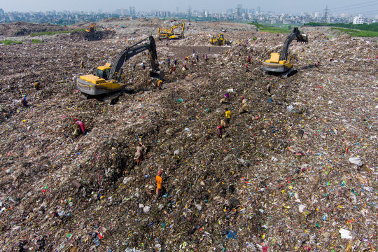 Aerial view of a vast, textured landscape of waste where excavators loom over the scene amidst scattered figures, Dhaka, Dhaka Division, Bangladesh.