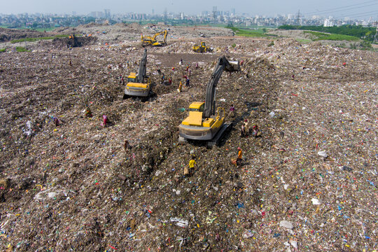 Aerial view of a vast landfill where heavy machinery and numerous people are dwarfed by the sheer volume of waste, Dhaka, Dhaka Division, Bangladesh.