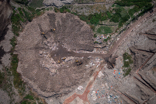 Aerial view of a massive landfill with scattered bulldozers working amidst piles of waste, Dhaka, Dhaka Division, Bangladesh.