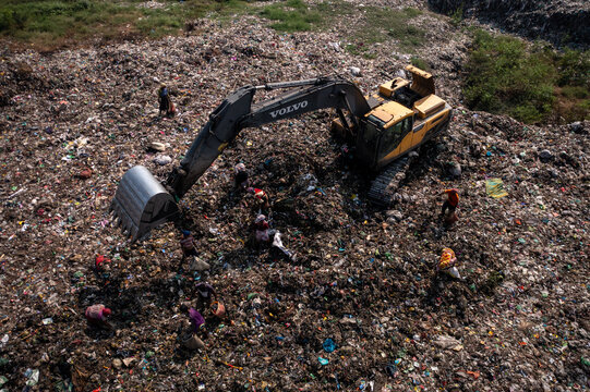 Aerial view of the vast landfill with heavy machinery moving refuse and workers scavenging amidst the waste, Dhaka, Dhaka Division, Bangladesh.