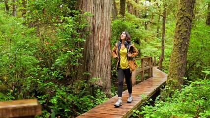 Female hiker enjoying a walk through lush green rainforest on vancouver island, british columbia, appreciating the tranquility and beauty of nature