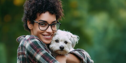 Young african female with glasses hugging a small dog outdoors