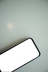 A smartphone is placed on a minimalist white table, copy space.