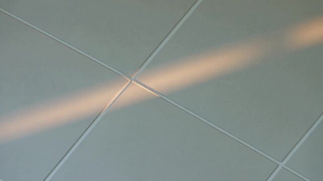 Sunlight streaming through a modern ceiling with square panels