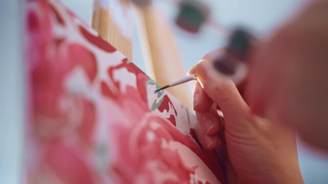 Tight Shot Brush Applying Green Leaf Strokes On Rose Canvas, Professional Illustrator Refining Edges At Easel In Bright Studio Precise Wrist Control, Thin Filbert Brush, And Crisp Highlights