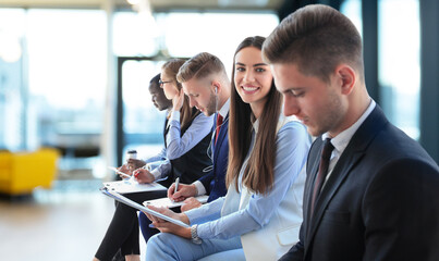 Smiling businesswoman looking at camera at seminar with her colleagues near by