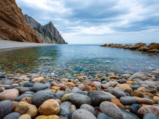 Rocky beach scene colorful stones lead to calm water under a cloudy sky with cliffs in the background