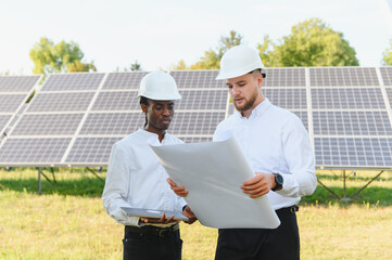 Engineers discussing solar panel blueprints at renewable energy farm