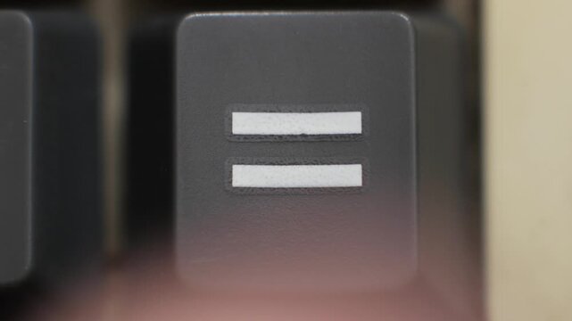 Macro close up of an equal sign key being pressed symbolizing equality, fairness and mathematical balance