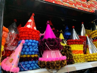 Colorful decorative ornaments knick knacks for birthday celebrations or religious celebration decorations sold in shops. The items include shiny, spherical red, green, gold, pink, and silver.