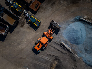 Aerial view of heavy machinery and piles of gravel contrasting with the dark asphalt below, creating an industrial landscape of textures and tones, Boston, Massachusetts, United States.