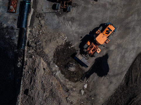 Aerial view of heavy machinery and construction equipment contrast against the rough, rocky terrain, casting long shadows across the site, Boston, Massachusetts, United States.