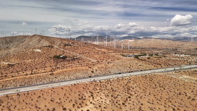 A cinematic flyover highlighting wind turbines turning in the warm desert breeze right off the I10 interstate 10 highway.