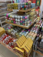 Colorful decorative ornaments knick knacks for birthday celebrations or religious celebration decorations sold in shops. The items include shiny, spherical red, green, gold, pink, and silver.