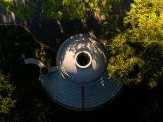 Aerial view of a circular, domed structure rises from the verdant embrace of trees in the Boston Public Garden, its stone steps casting long shadows, Boston, Massachusetts, United States.