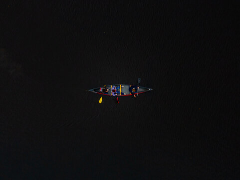 Aerial view of a canoe with people floating on the dark waters creating a striking contrast, Boston, Massachusetts, United States.