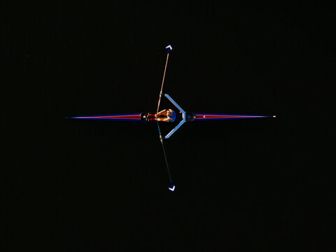 Aerial view of a lone rower gliding across the dark waters, oars outstretched like delicate wings, Boston, Massachusetts, United States.