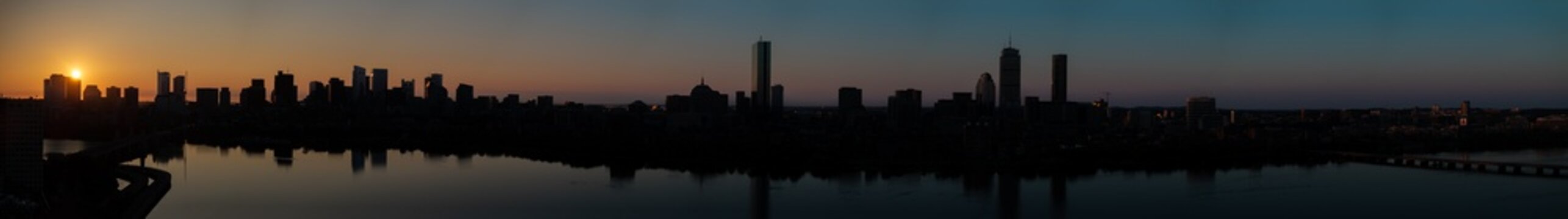 Aerial view of the silhouetted Boston skyline, including the Custom House Tower and Prudential Center, reflecting in the Charles River at dusk, Boston, Massachusetts, United States.