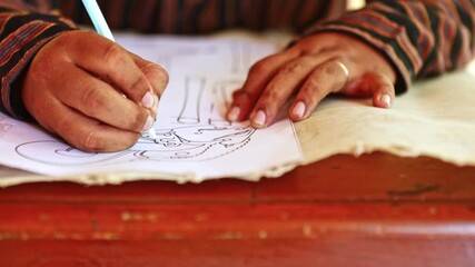Close up of hands drawing a traditional Buddhist symbol