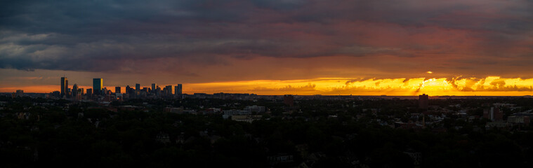 Aerial view of the Boston skyline silhouetted against a vibrant, fiery sunset, with dark clouds creating a dramatic contrast over the city, Boston, Massachusetts, United States.