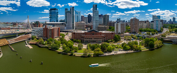 Aerial view of the Charles River flowing past lush green trees and iconic buildings, with the Boston skyline shimmering in the distance, Boston, Massachusetts, United States.