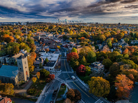 Aerial view of autumn's fiery hues paint the trees below a dramatic sky as it meets the Boston skyline in the distance, Boston, Massachusetts, United States.