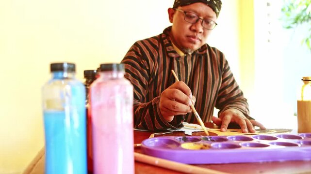 Indonesian artist painting a traditional wayang puppet
