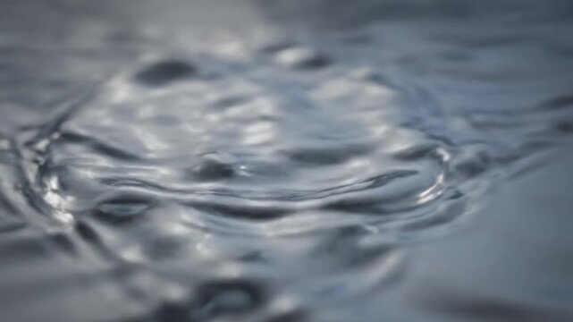 Abstract close-up of rippling water surface with subtle concentric circles creating a mesmerizing and fluid visual effect