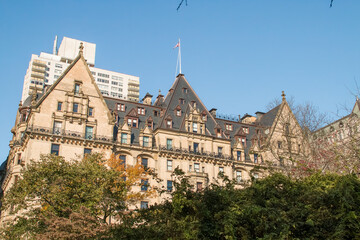 Tejado del edificio The Dakota sobresaliendo sobre los &aacute;rboles de Central Park, Nueva York, EEUU. Ramas de los &aacute;rboles de los jardines de Central Park en oto&ntilde;o. Noviembre 2019.