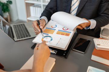 A collaborative startup meeting showing professionals reviewing financial charts and discussing strategic ideas in a modern office setting.