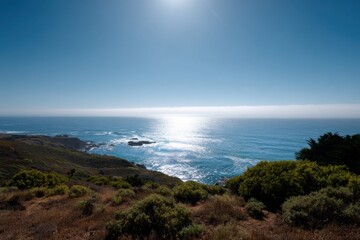 Sunlit coastal landscape with ocean horizon and rugged shoreline