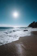 Sunlit coastal landscape with glistening waves and clear sky