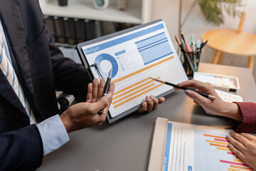 A collaborative startup meeting showing professionals reviewing financial charts and discussing strategic ideas in a modern office setting.