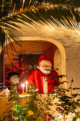 A sculpture of Santa Claus celebrating Christmas, view through the palm leaves 
