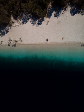 Aerial view of the striking contrast between the dark, inky water and the pristine white sands kissed by the sun, Kgari, Queensland, Australia.