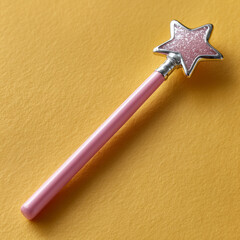 Fototapeta premium Pink star magic wand with glitter on yellow background.