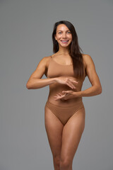 Full-length portrait of confident athletic woman posing with calm expression